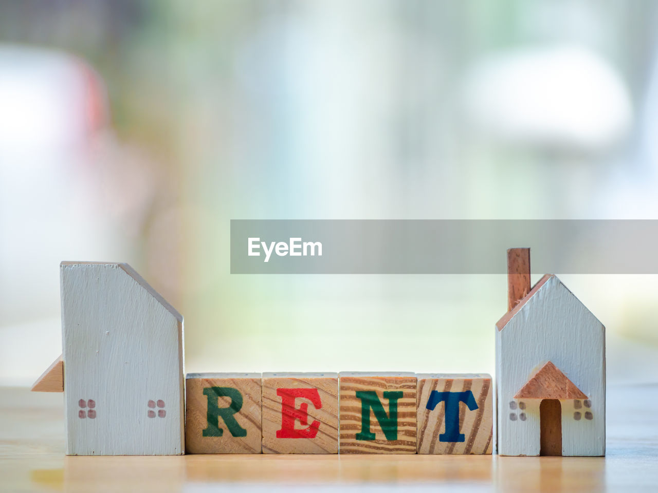 Close-up of model home with rent text on table
