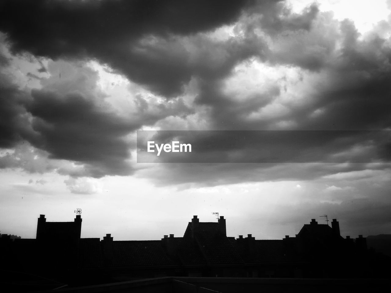 Silhouette houses against cloudy sky