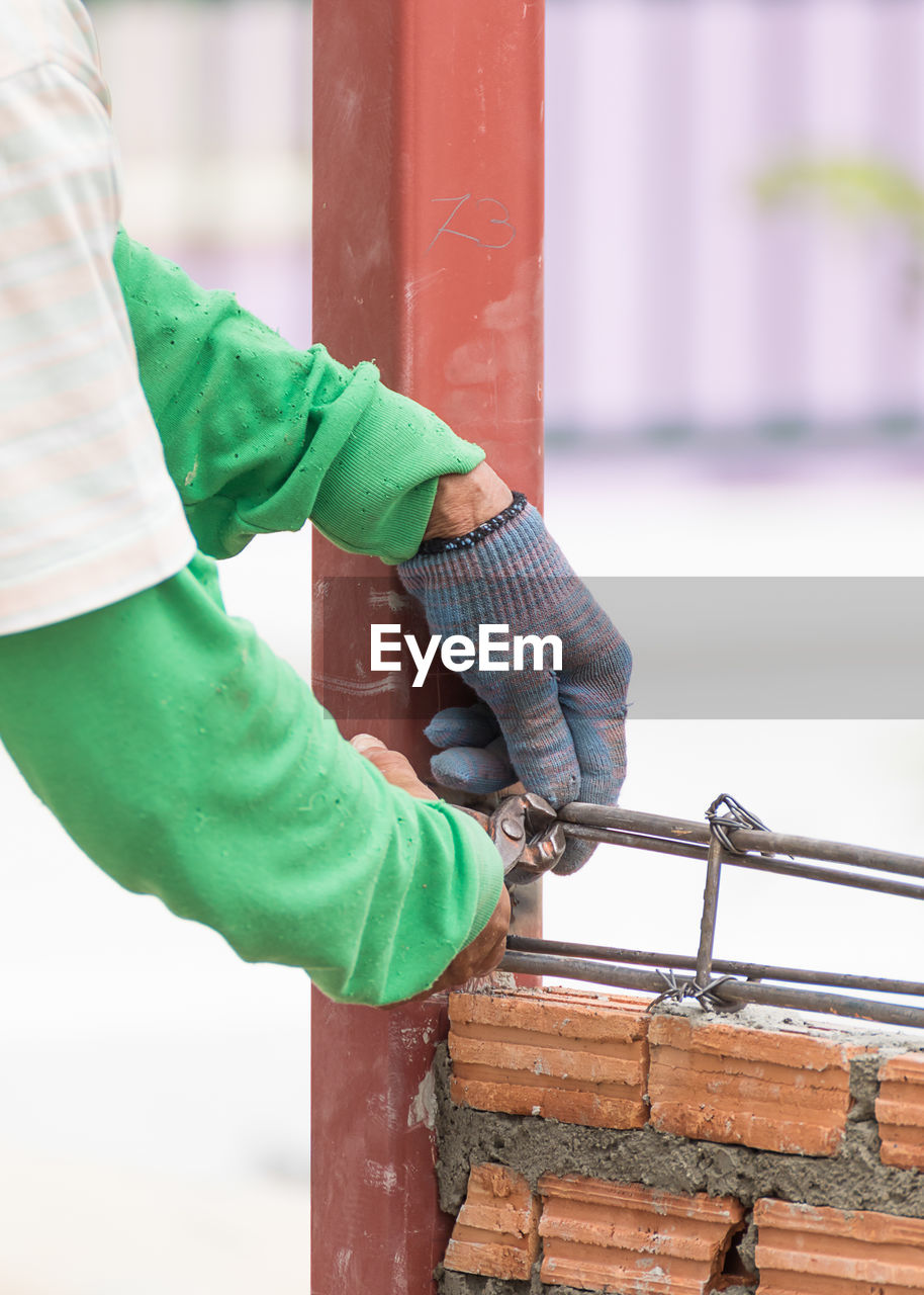 Workers using steel wire and pincers rebar before concrete is poured on brick wall