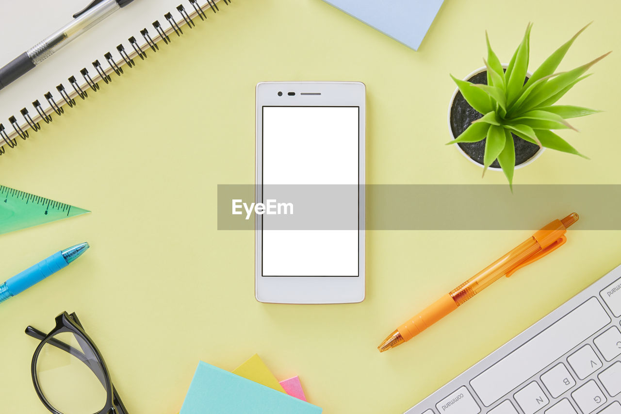 Vertical mobile phone or smart phone mock up on office desk table with office supplies as keyboard