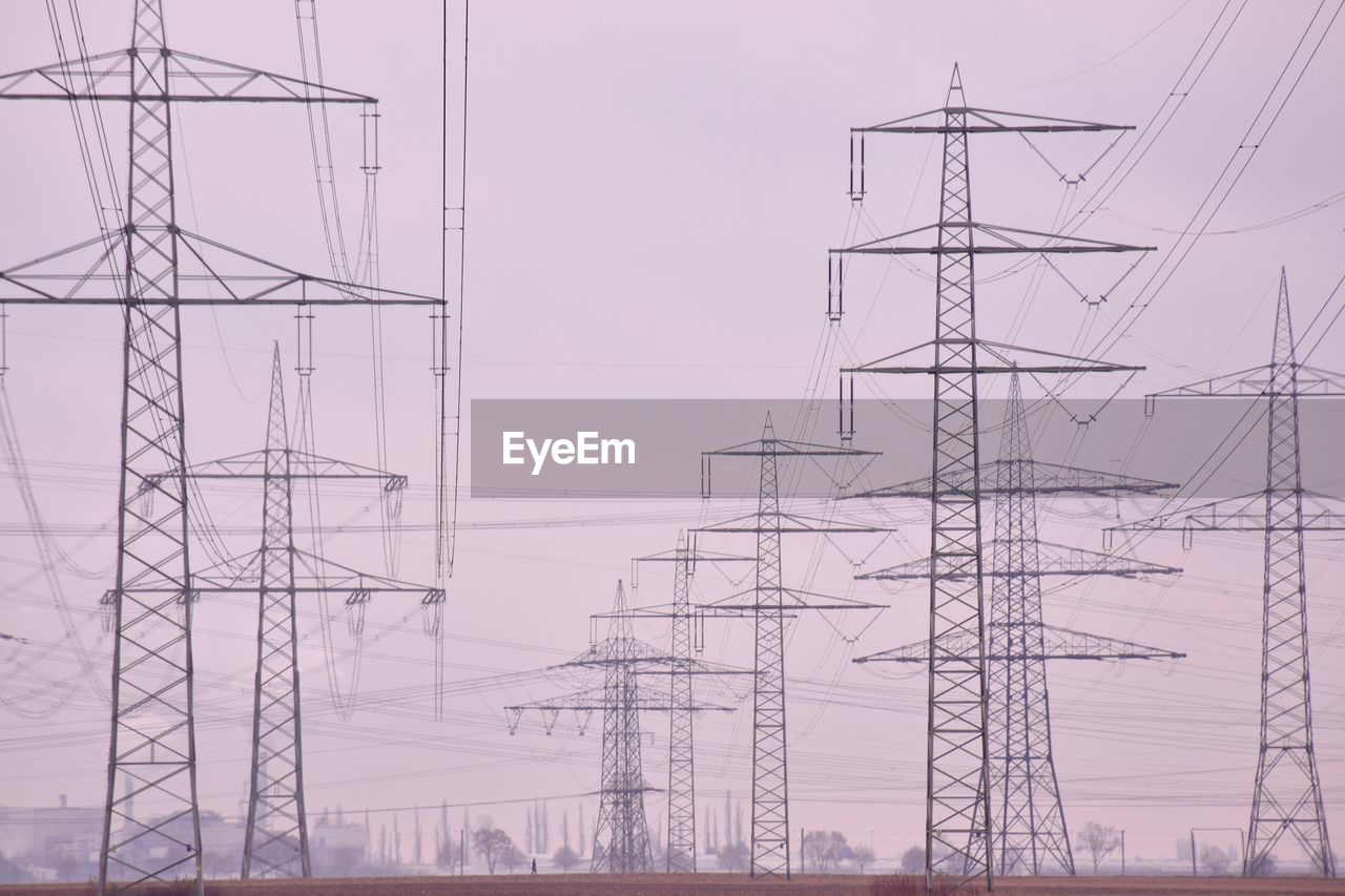 Low angle view of electricity pylons against sky