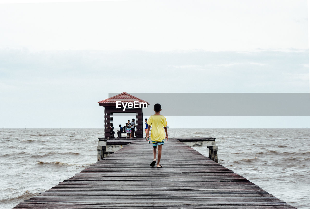 FULL LENGTH REAR VIEW OF MAN WALKING ON PIER