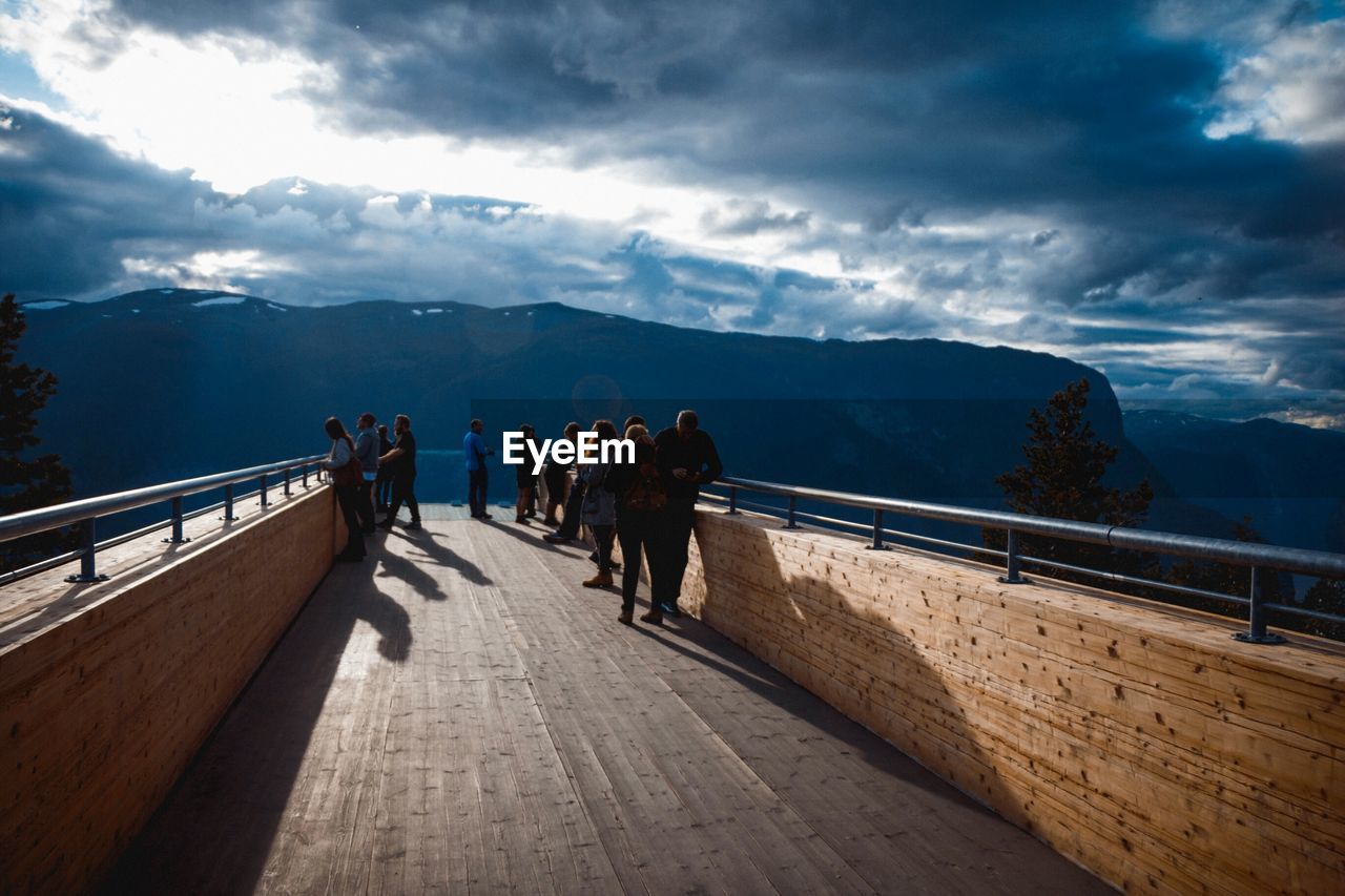 PEOPLE ON MOUNTAIN RANGE AGAINST SKY