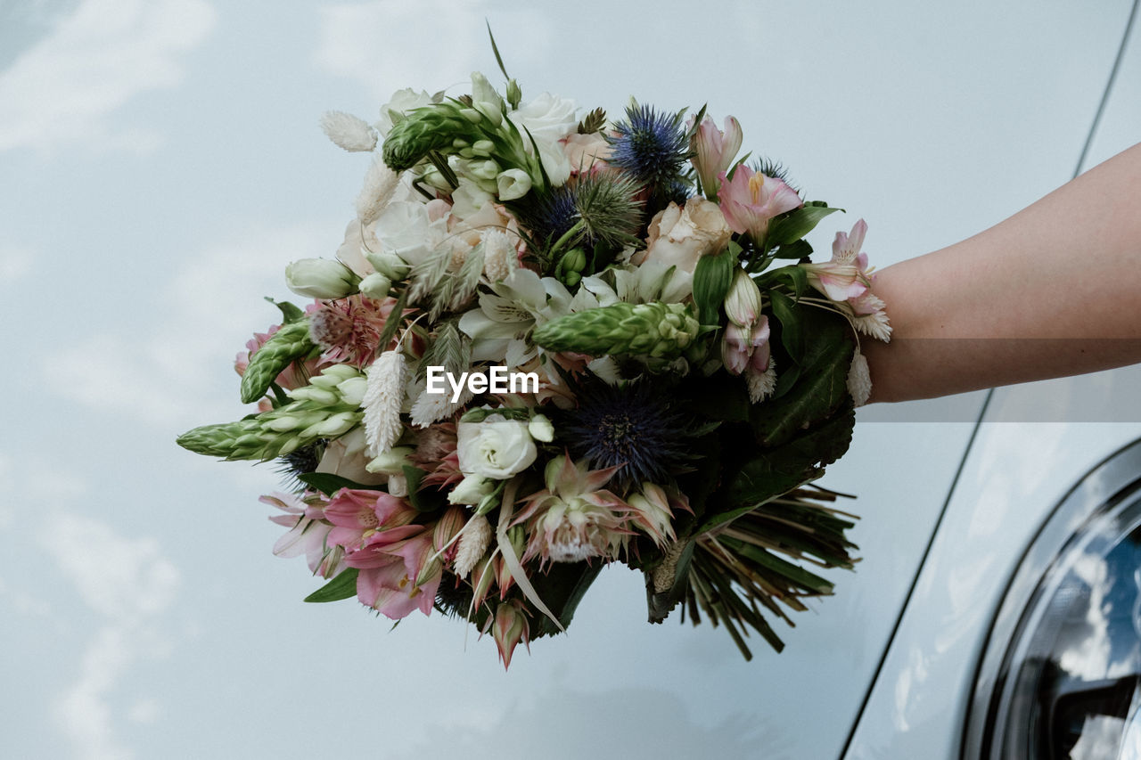 Midsection of woman holding bouquet of flowering plant