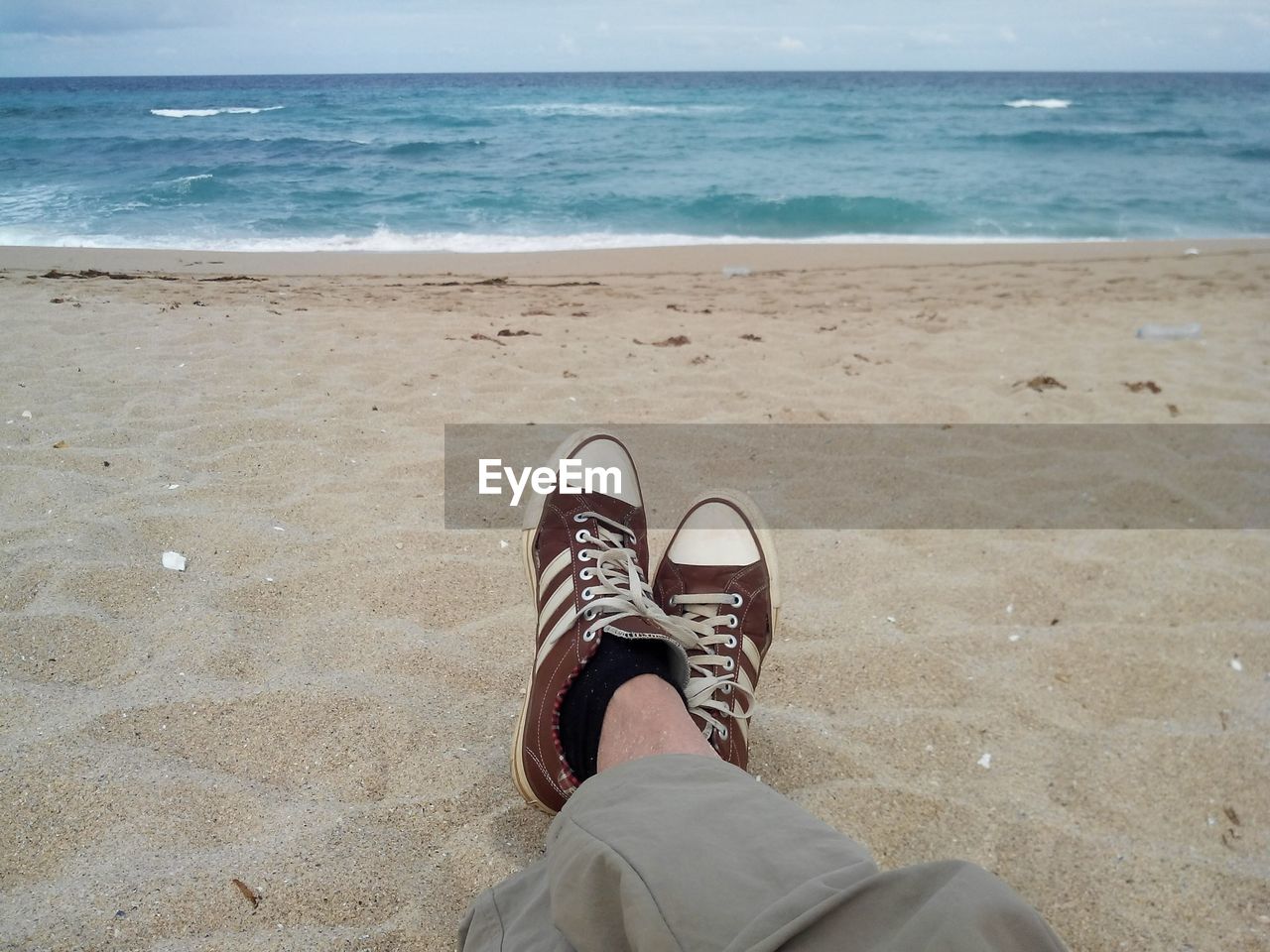 LOW SECTION OF MAN STANDING AT BEACH