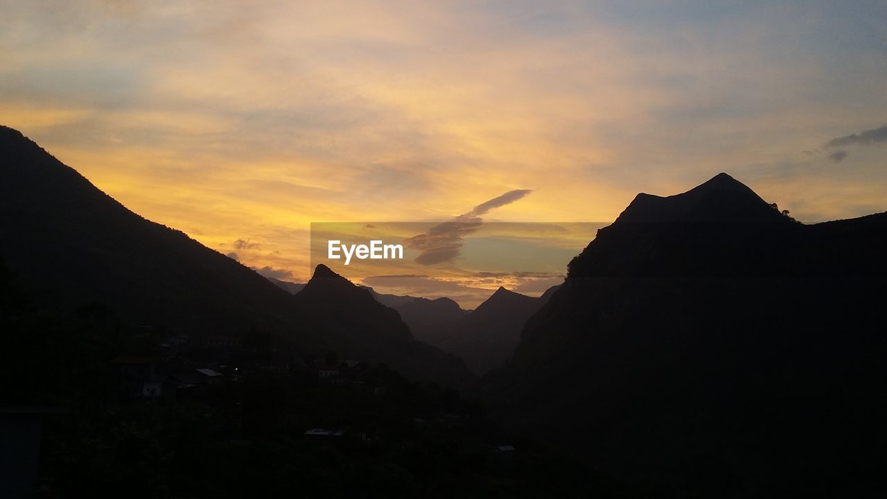 Silhouette of mountain against cloudy sky during sunset