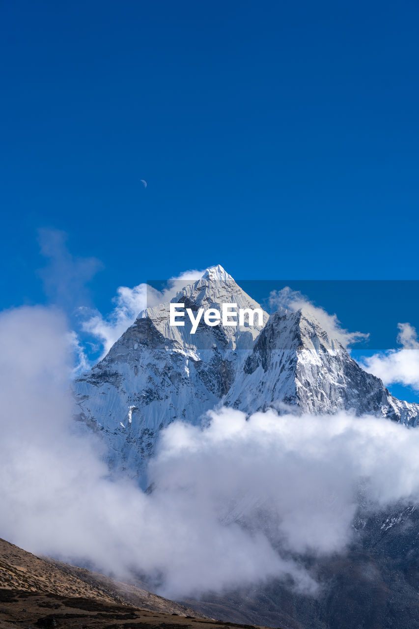 Scenic view of snowcapped mountains against blue sky