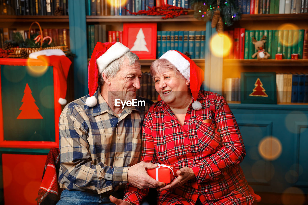 Elderly woman giving present to her beloved husband.