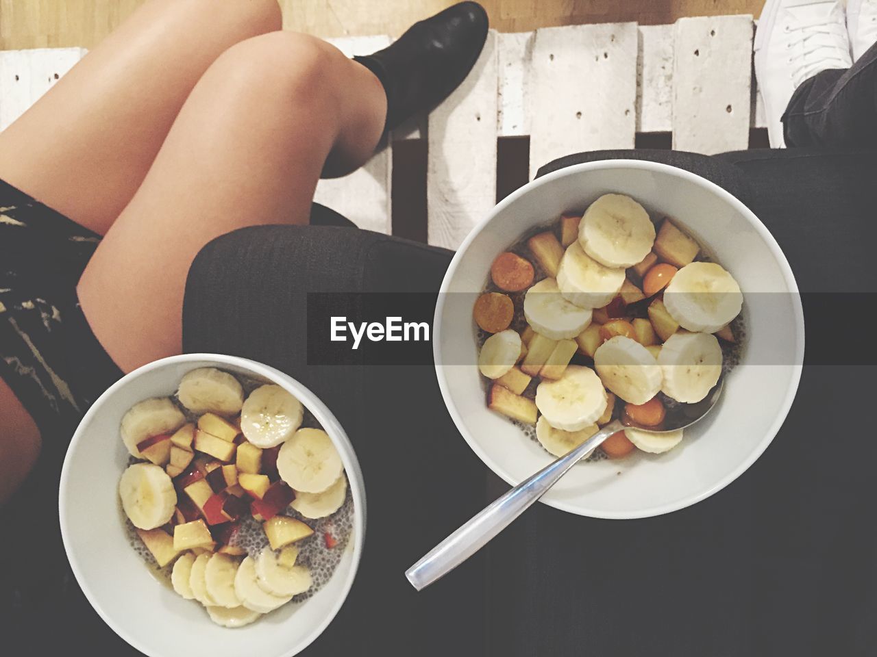 Low section of woman with fruit bowls on sofa