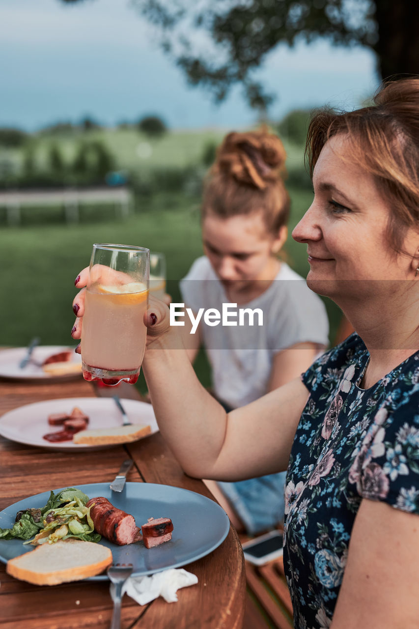 Family having a meal from grill during summer picnic outdoor dinner in a home garden