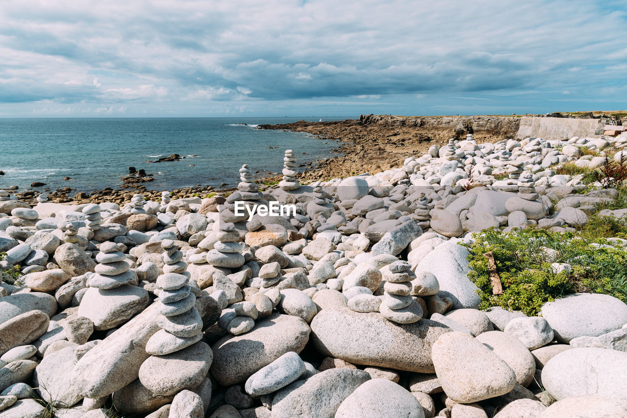 Stack of stones by sea shore against sky