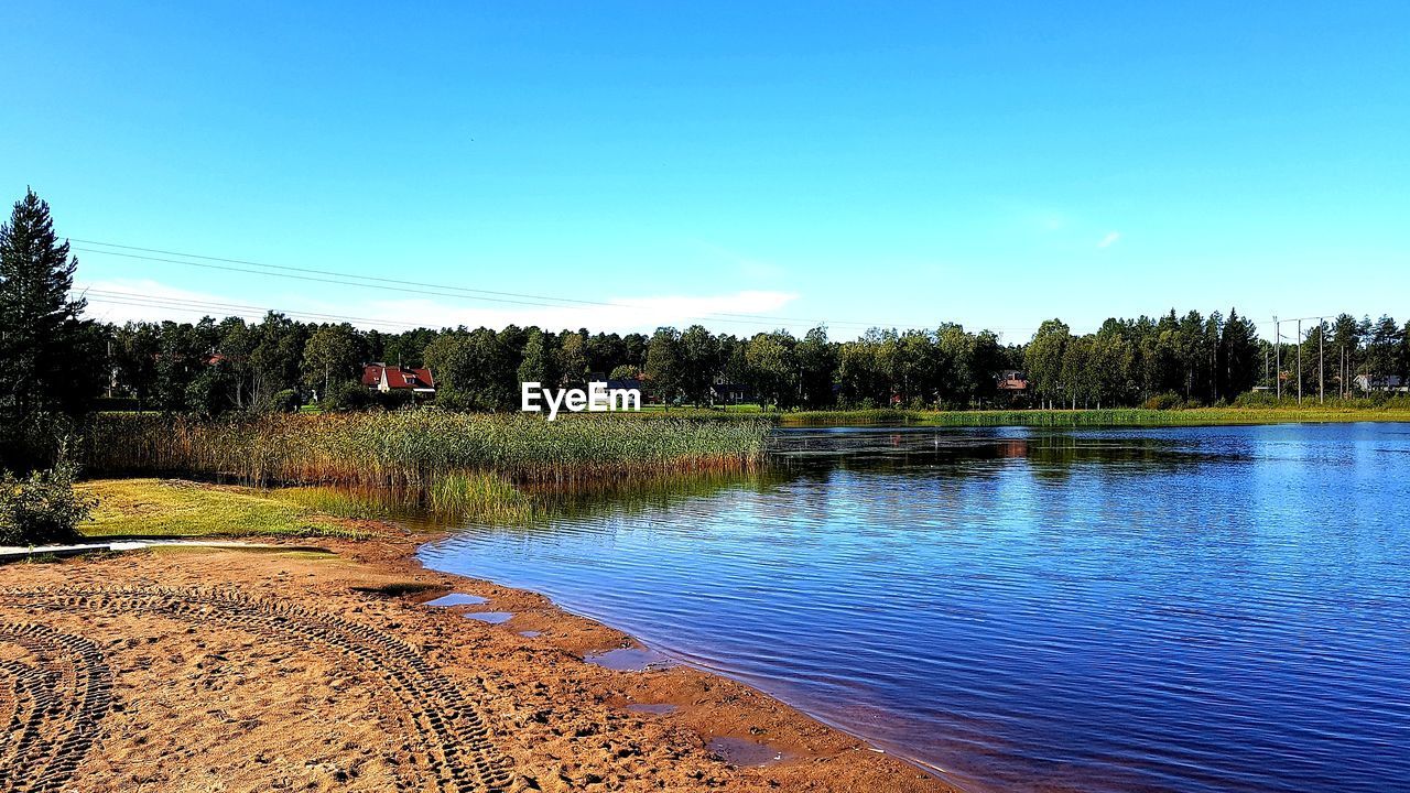 Scenic view of lake against clear blue sky