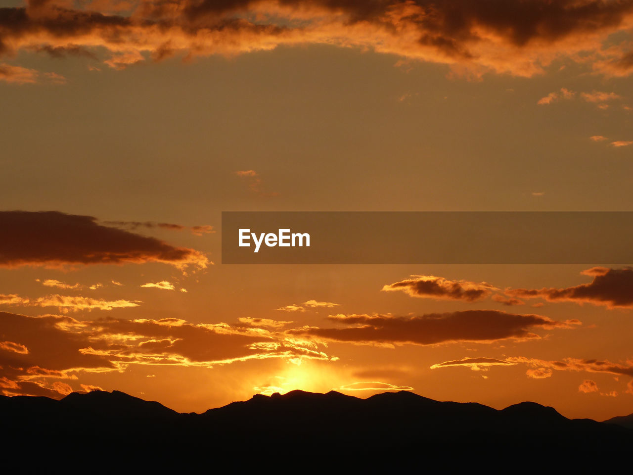 Scenic view of silhouette mountains against orange sky during sunset