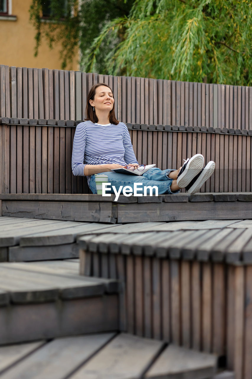 Rear view of woman sitting on staircase, woman blogger or freelancer resting in a public place 