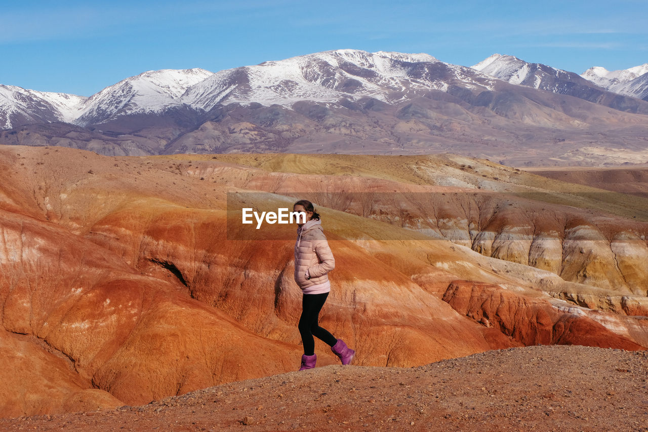 Smiling mid adult woman walking on mountain against sky