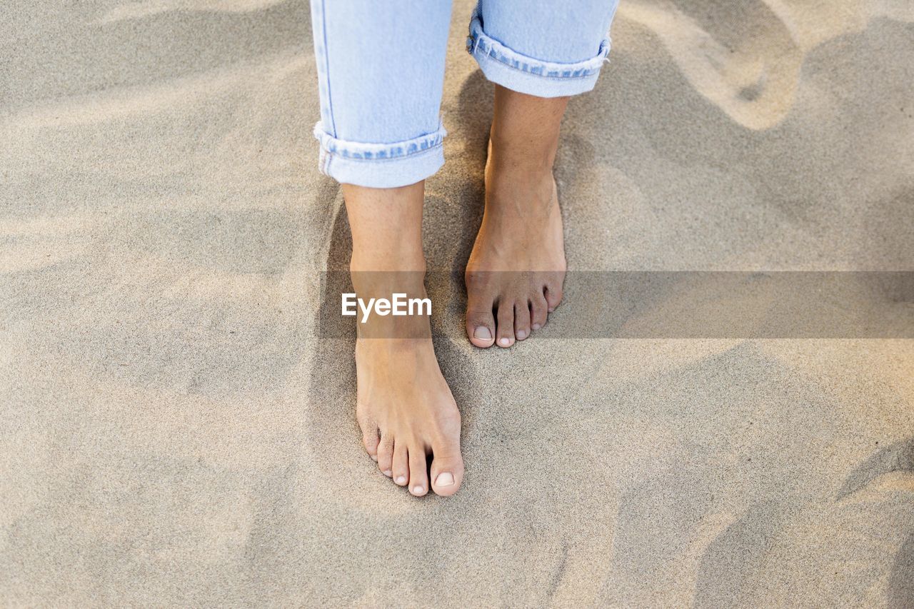 low section of woman standing on sand at beach