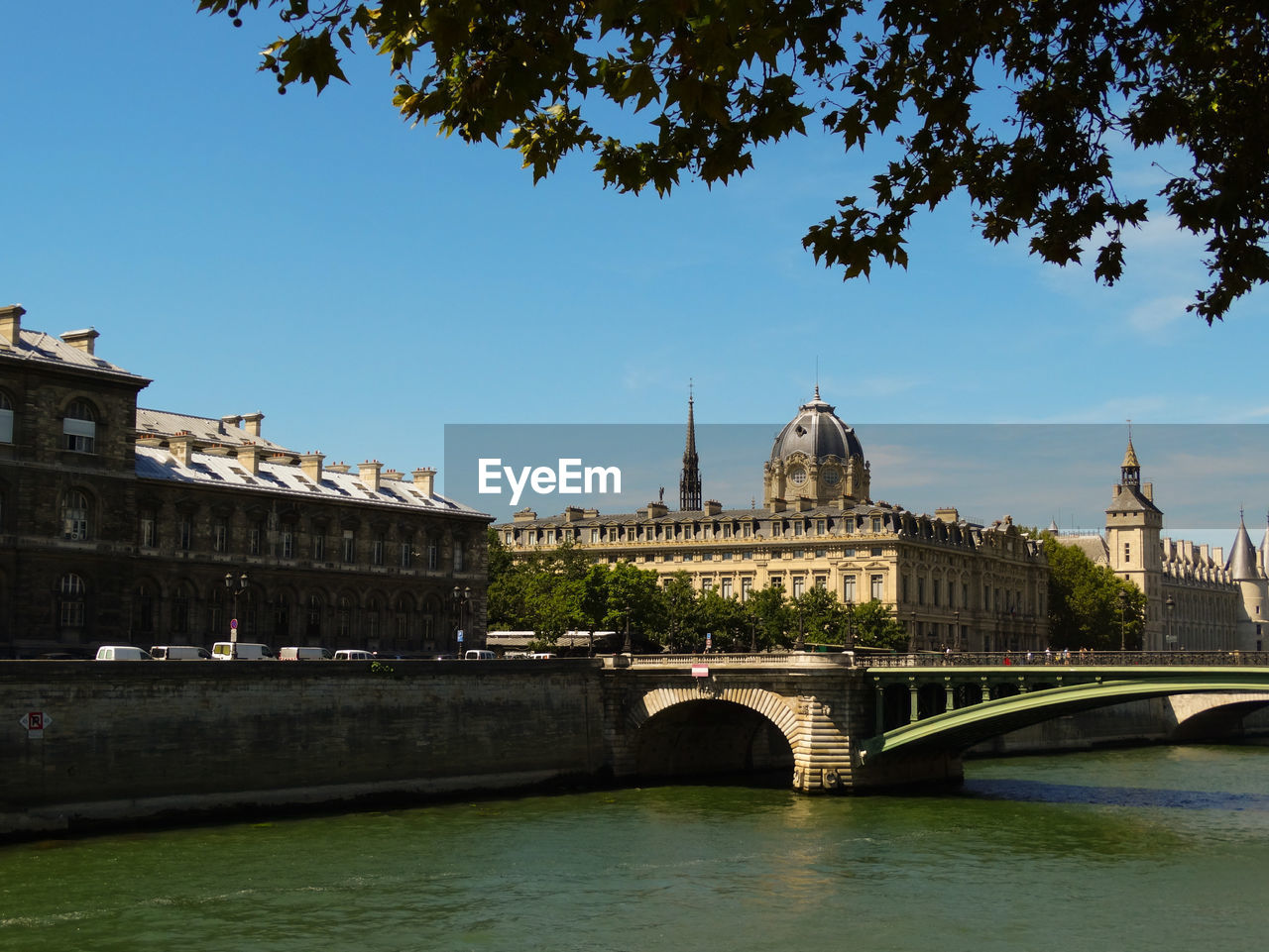 Arch bridge over river against sky in city