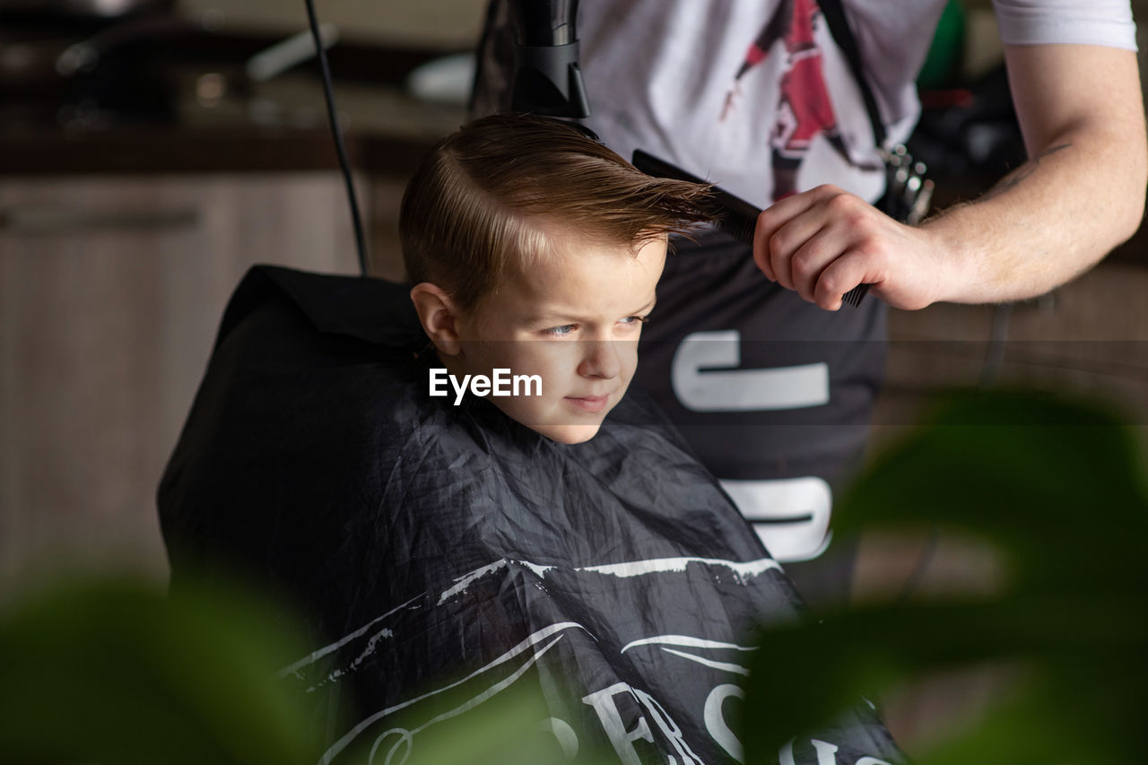 Midsection of barber cutting hair of boy