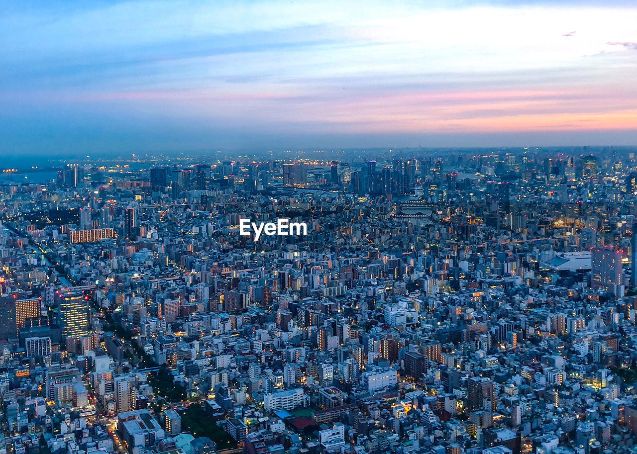 HIGH ANGLE VIEW OF ILLUMINATED CITY BUILDINGS AGAINST SKY