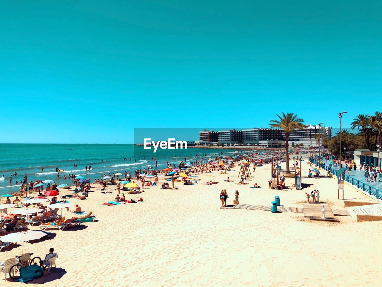 People on beach against clear blue sky