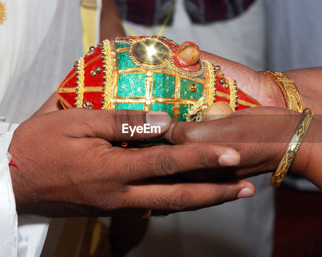 Cropped hands of couple holding shiny coconut during ceremony