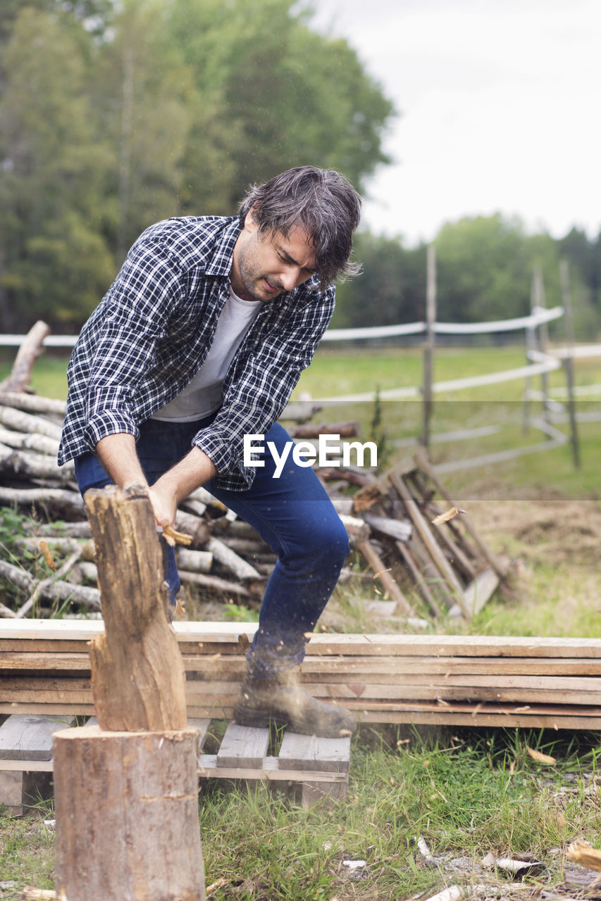Mid adult man cutting firewood at yard