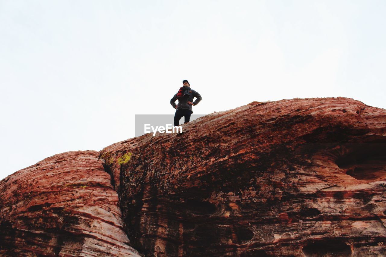 Man standing on rock against clear sky