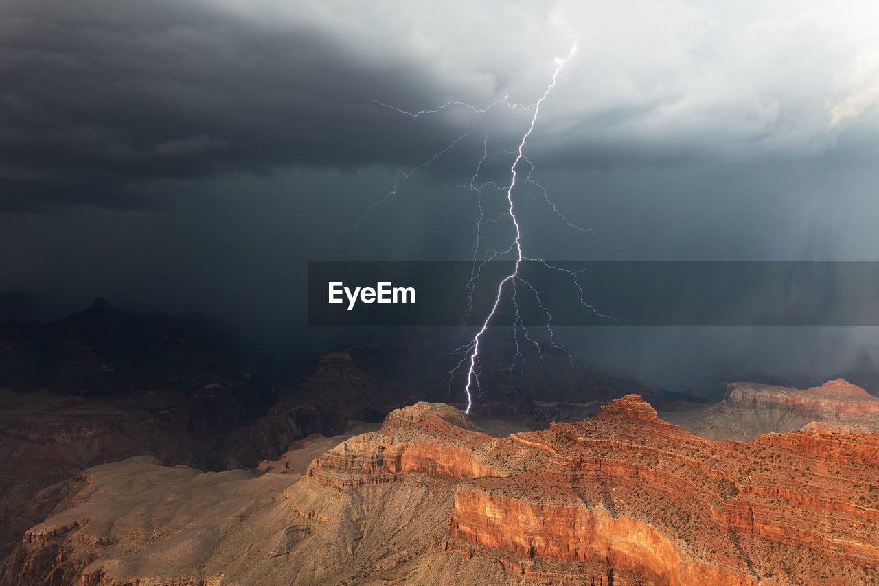 A bright lightning bolt strikes a cliff in the grand canyon during a summer thunderstorm.