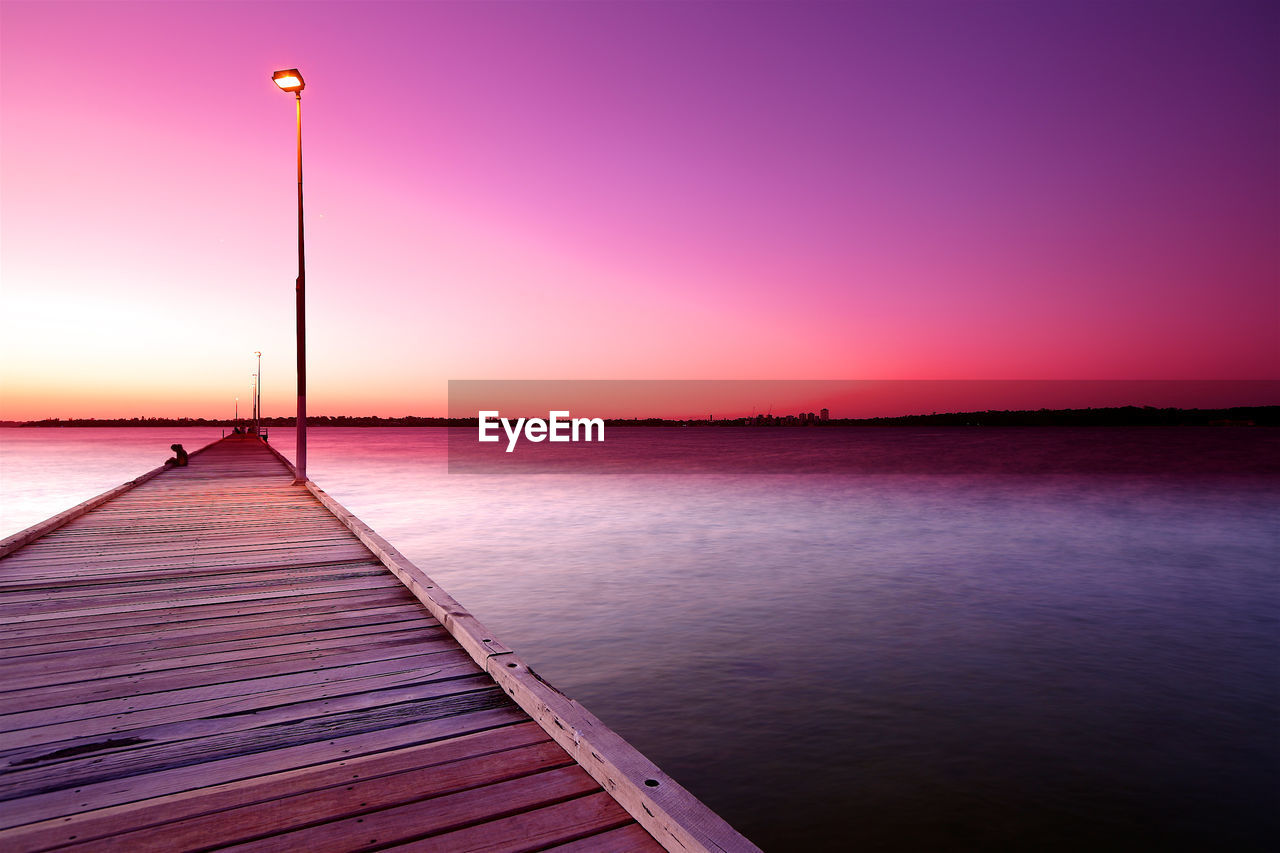 Pier over sea against sky during sunset