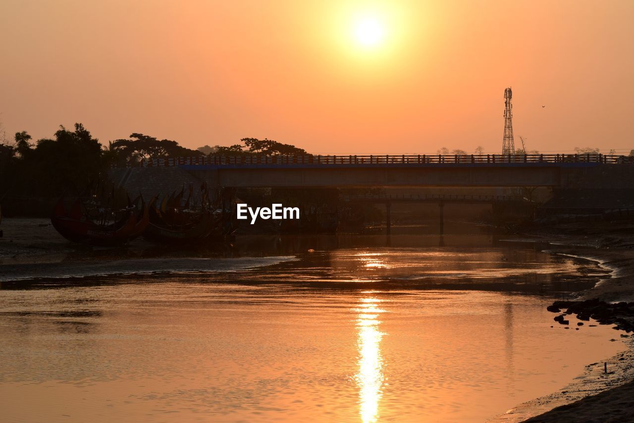 BRIDGE OVER RIVER AGAINST SKY AT SUNSET