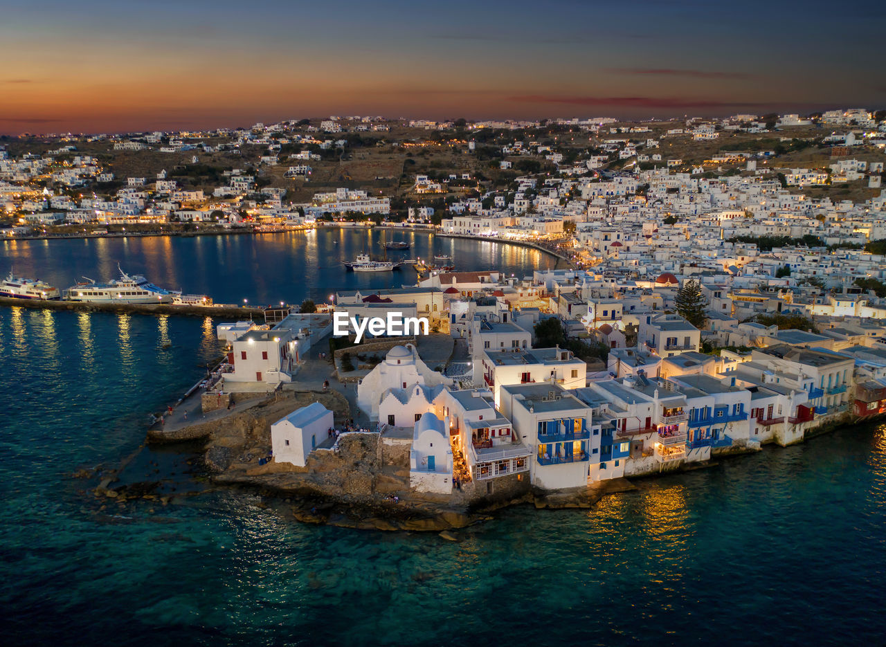 High angle view of townscape by sea during sunset