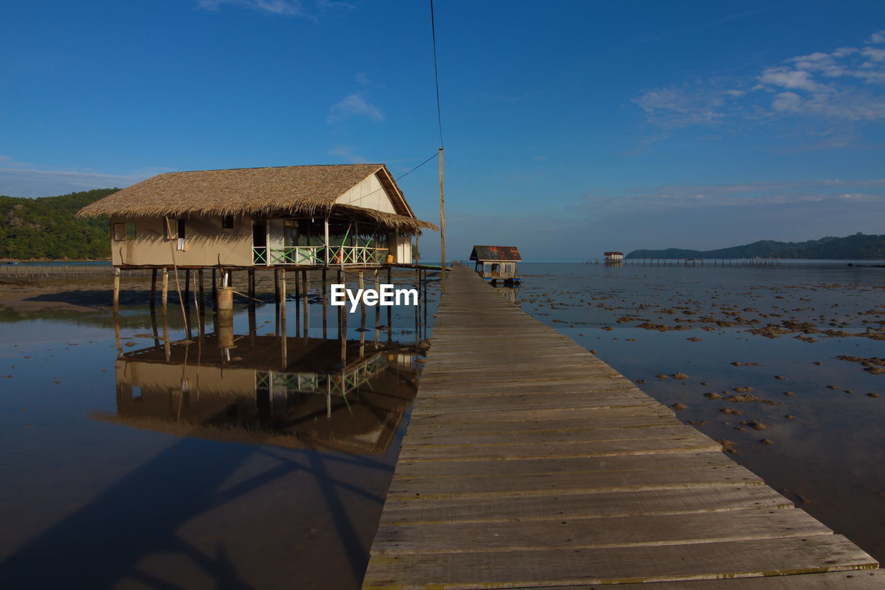 WOODEN PIER AMIDST HOUSES AGAINST SKY