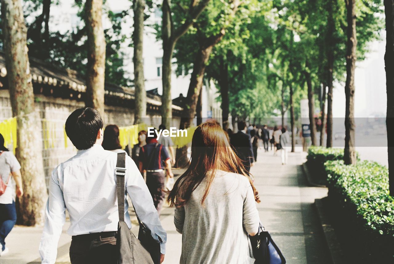 Rear view of people walking on sidewalk