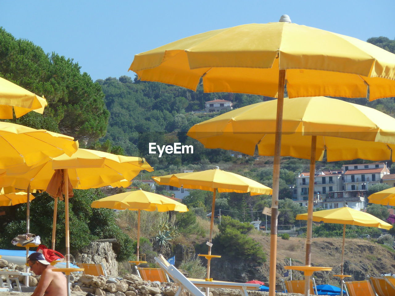 WOMAN WITH UMBRELLA ON BEACH AGAINST SKY