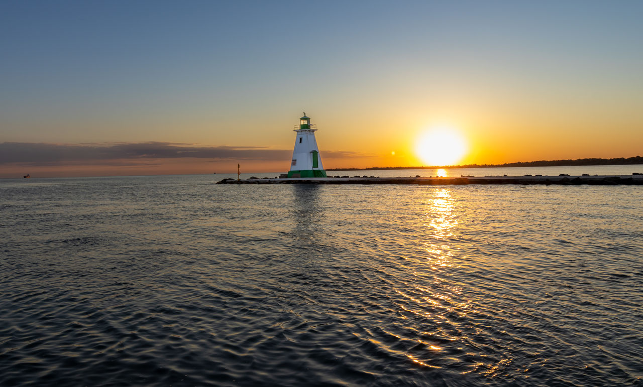 lighthouse, sky, water, guidance, sea, sunset, horizon, architecture, ocean, tower, nature, built structure, dawn, building, building exterior, travel destinations, scenics - nature, reflection, evening, travel, coast, tranquility, security, beauty in nature, cloud, sunlight, protection, no people, beach, shore, tranquil scene, land, nautical vessel, wave, clear sky, orange color, outdoors, silhouette, sun, idyllic, tourism, horizon over water, coastline, landscape, transportation, copy space, afterglow, illuminated, bay