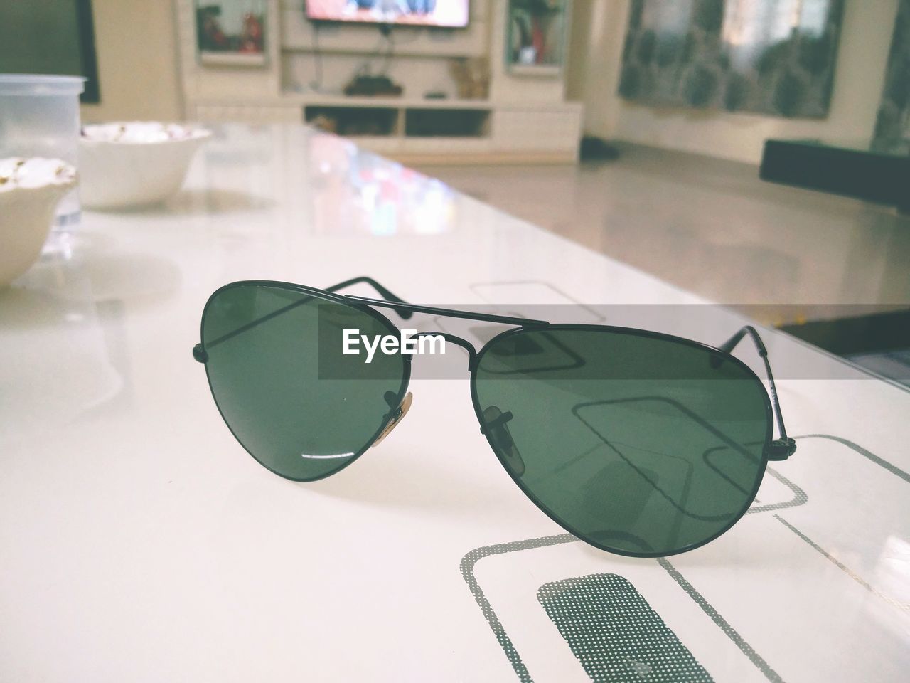 CLOSE-UP OF SUNGLASSES ON TABLE IN MIRROR