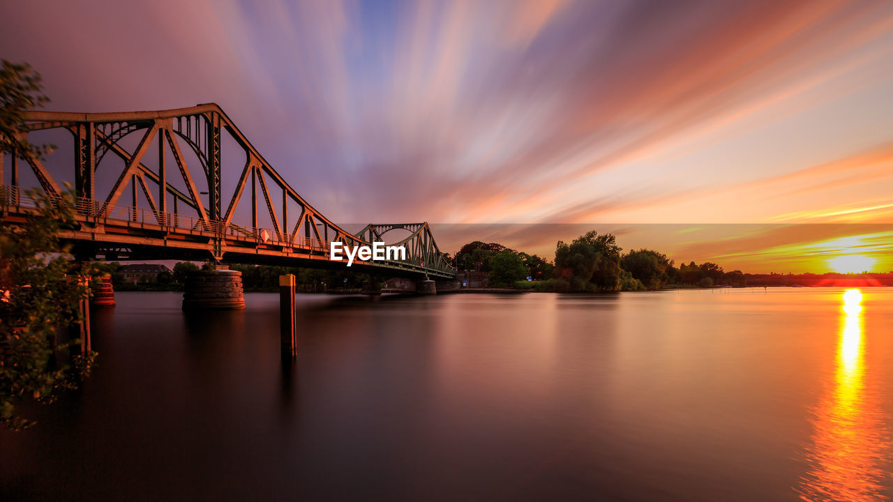 Glienicke bridge over river havel against sky during sunset