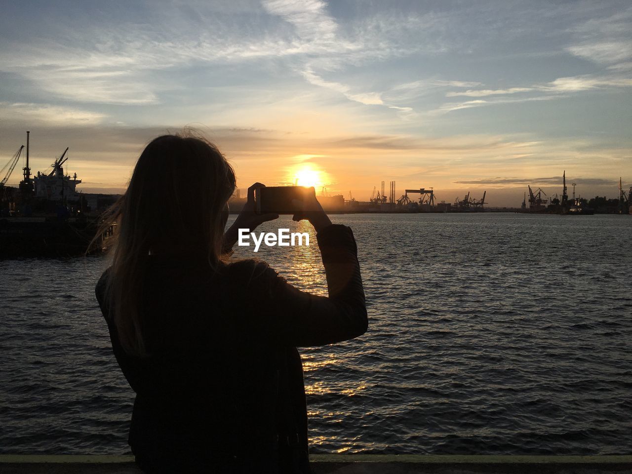 REAR VIEW OF WOMAN PHOTOGRAPHING SEA AGAINST SKY