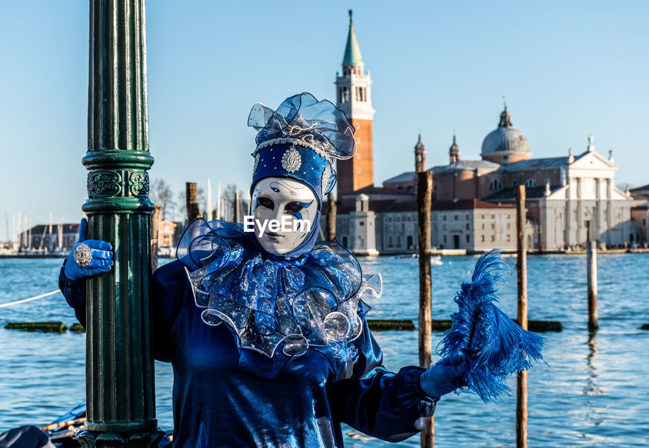 Woman wearing mask and costume against sea