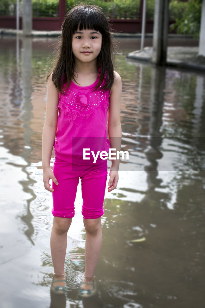 Portrait of cute girl standing on flooded area