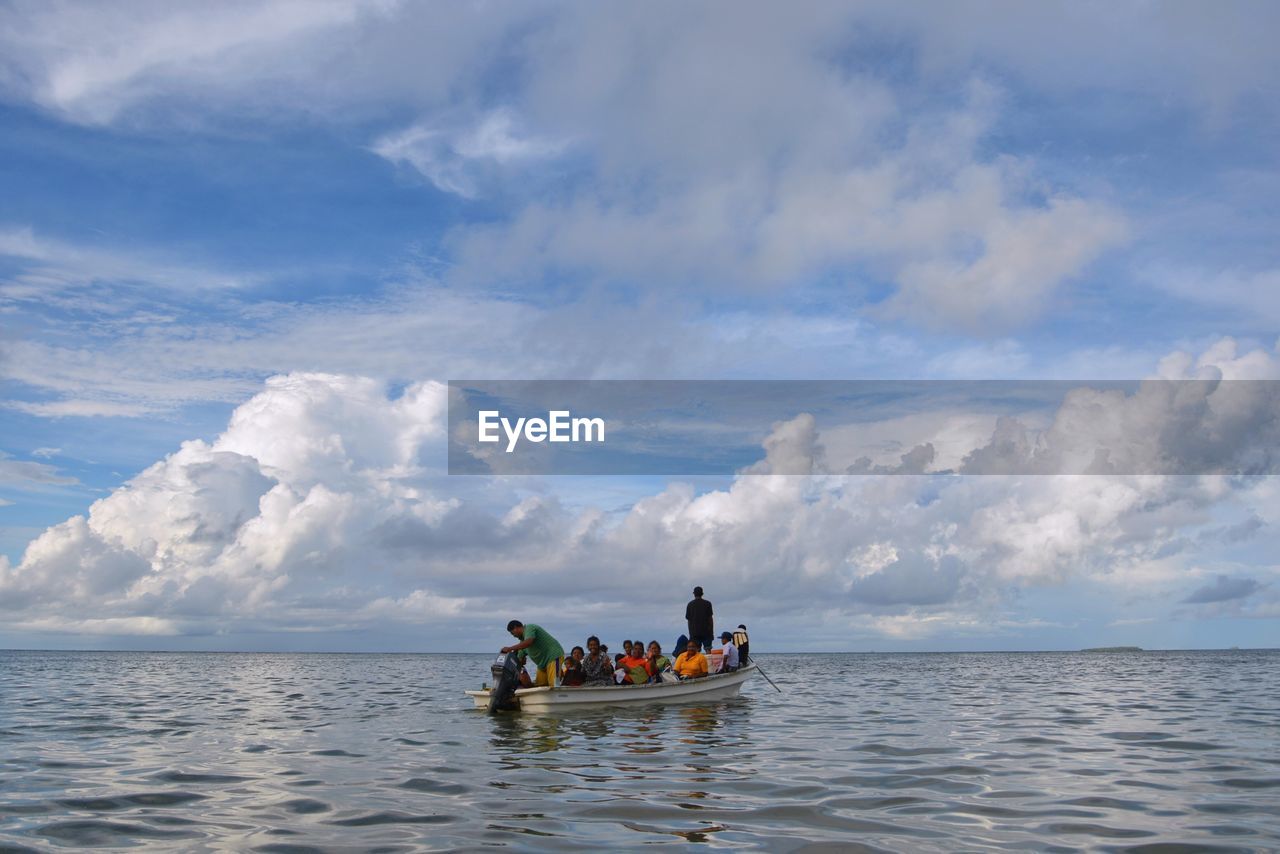 People sitting on boat in sea against sky