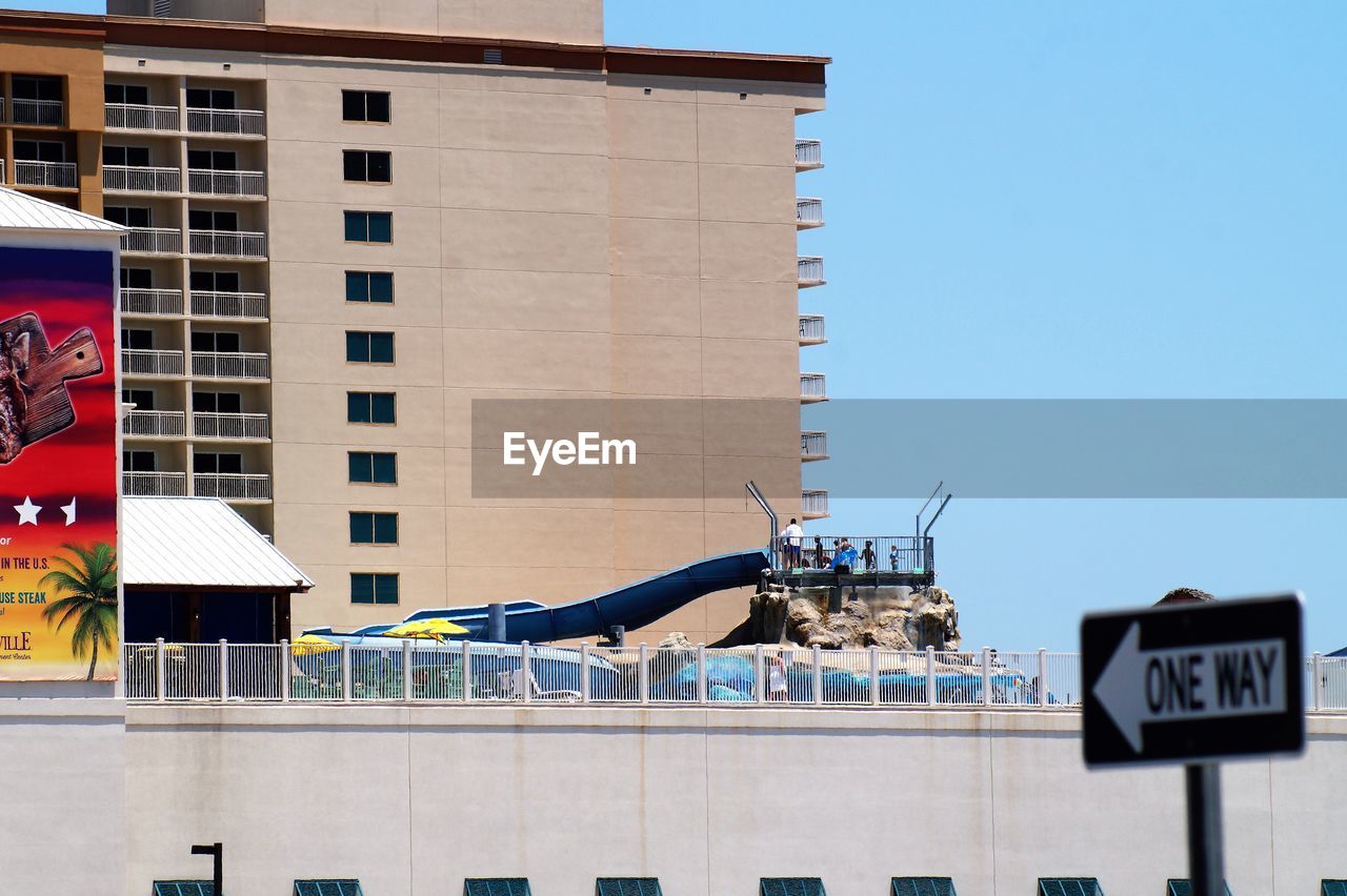 LOW ANGLE VIEW OF TEXT ON BUILDING AGAINST CLEAR BLUE SKY