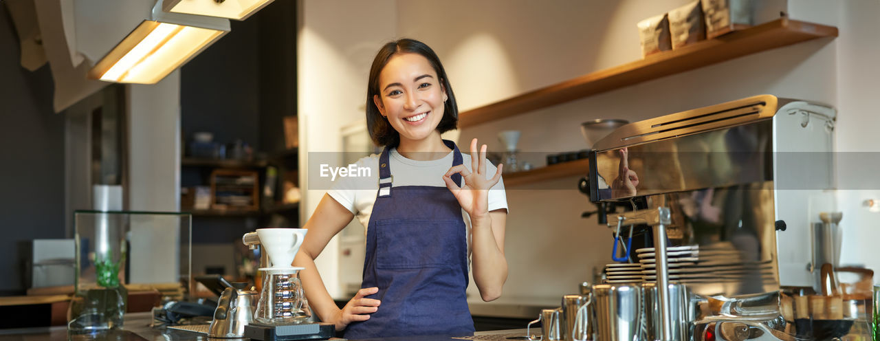 portrait of young woman using mobile phone while sitting at table