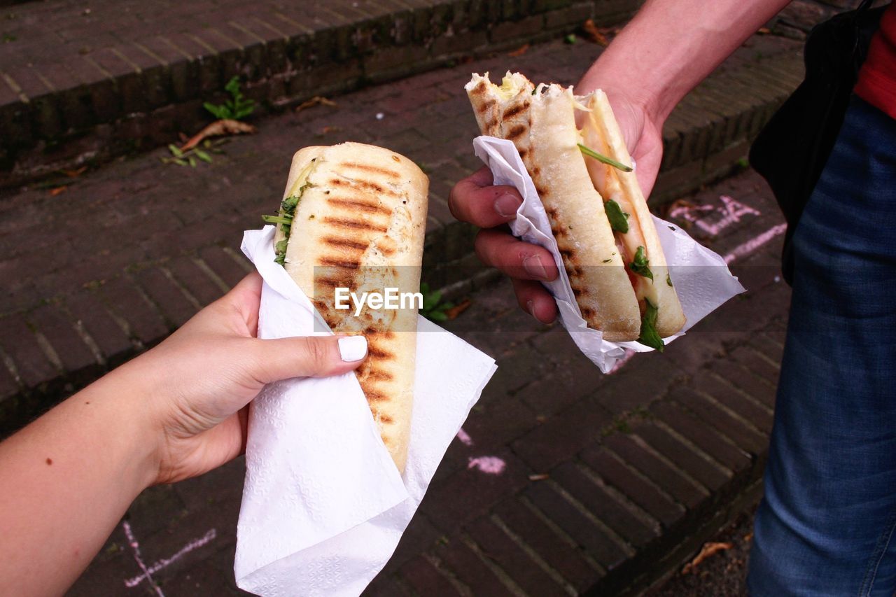 Cropped image of friends holding panini on steps