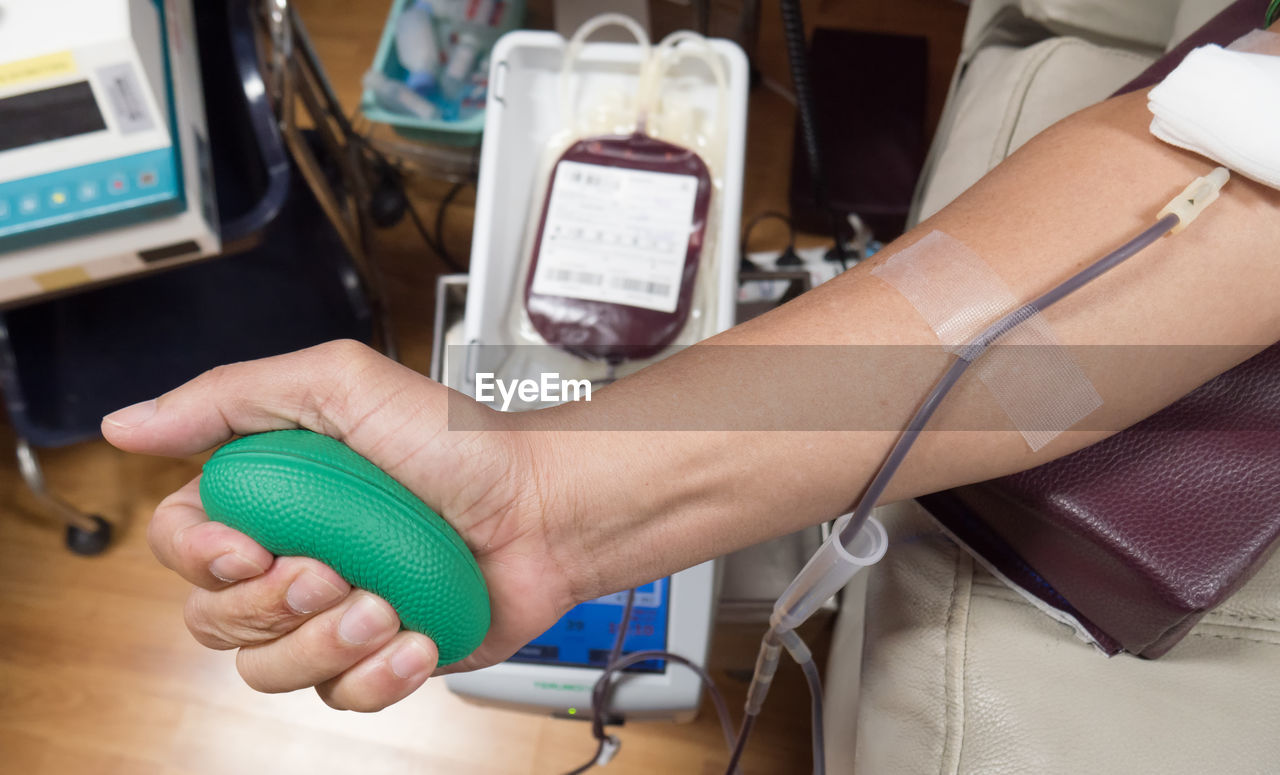 Man holding ball while donating blood in hospital