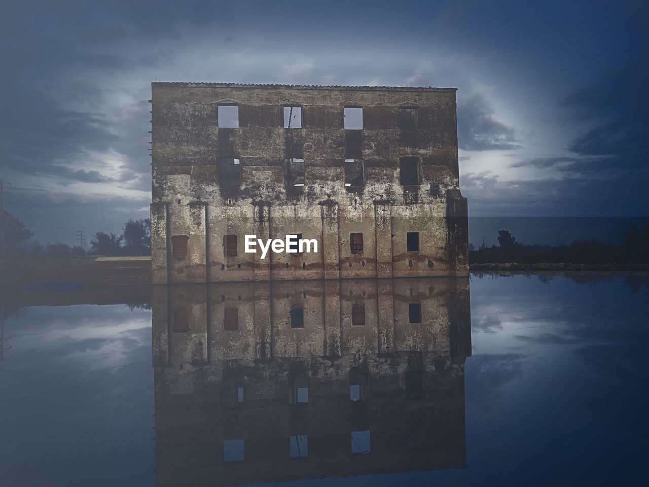 Reflection of building in lake against sky