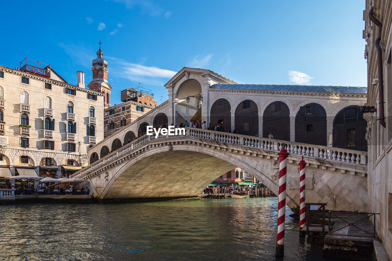 ARCH BRIDGE OVER RIVER AGAINST BUILDINGS