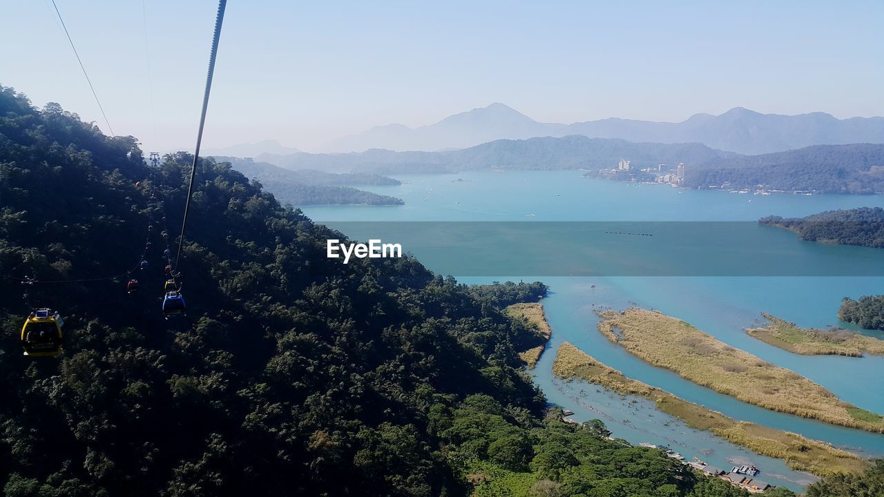 OVERHEAD CABLE CAR OVER SEA AGAINST SKY