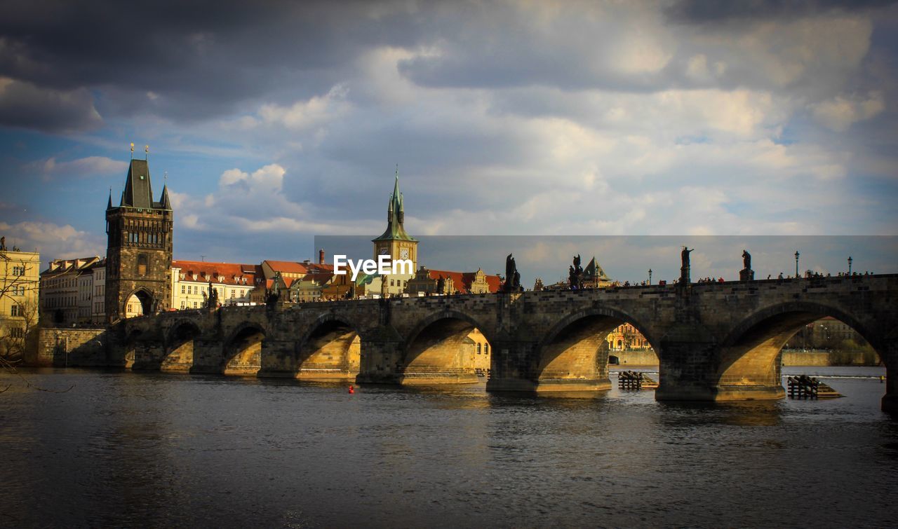 ARCH BRIDGE OVER RIVER AGAINST BUILDINGS