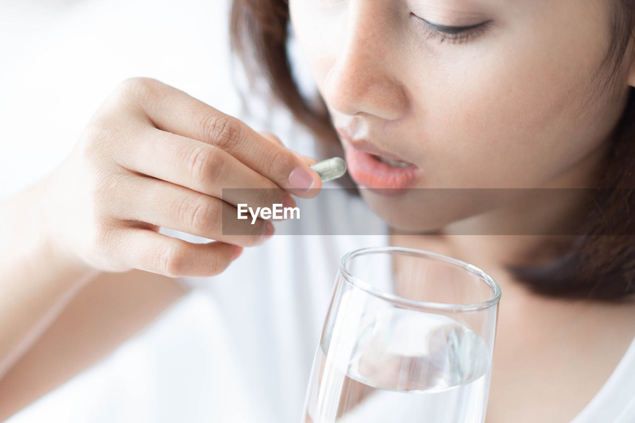 Close-up of woman taking medicine at home